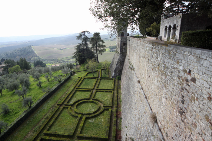 Muralha, jardim e algumas oliveiras a esquerda