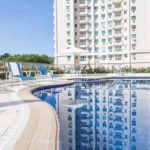 Piscina com esteiras, vista de um prédio e árvores ao fundo